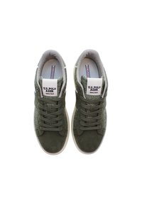 Gröna mocka- och tygskor med texturerade meshpaneler, platta snören, vadderad krage och en vit gummisula. Logotyp synlig på tungan.