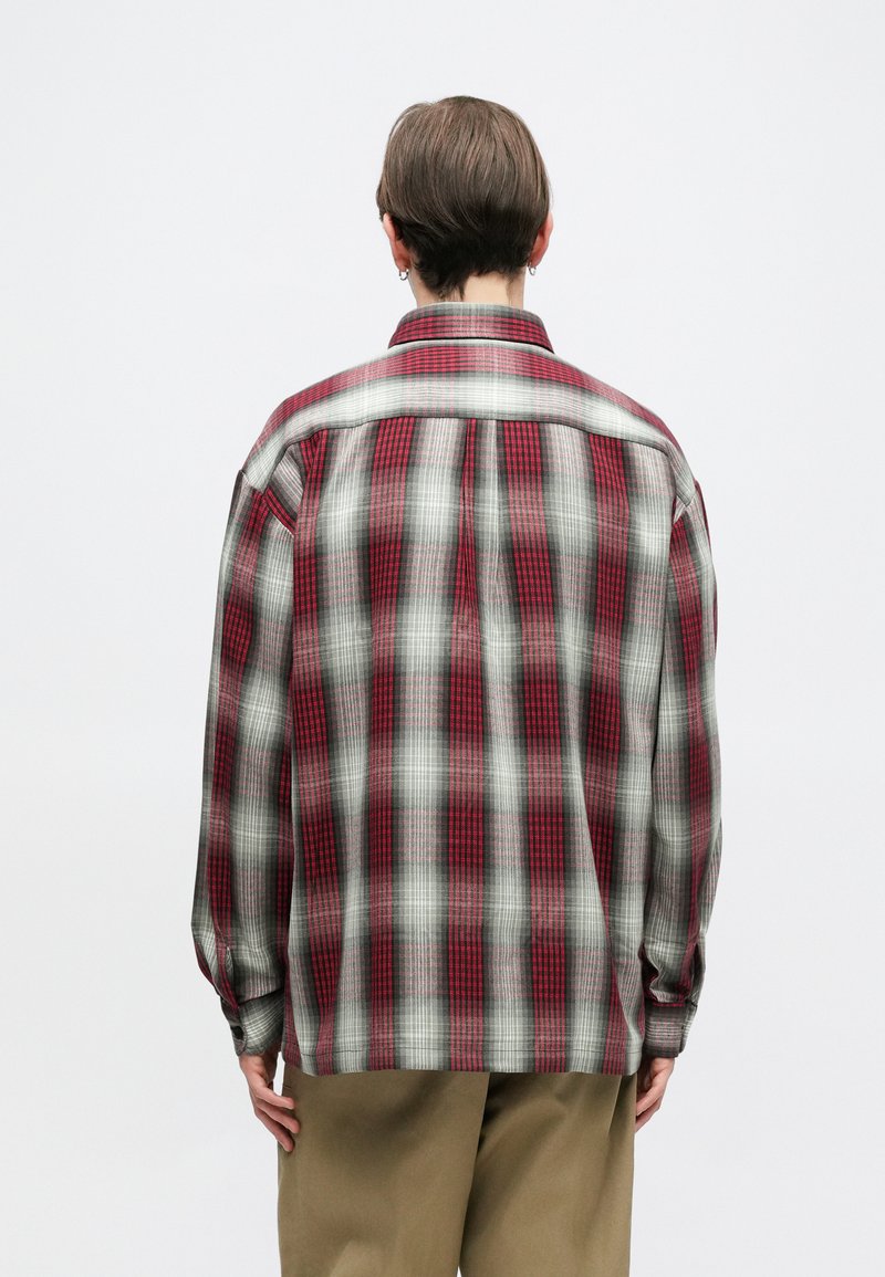Red and gray plaid shirt with long sleeves and a relaxed fit. Features a collar and back yoke detail in a soft, lightweight fabric.