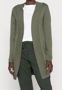 Oliegrøn cardigan med ribbet krave og forstykke, lange ærmer og en afslappet pasform. Kombineret med en hvid T-shirt og grønne bukser.