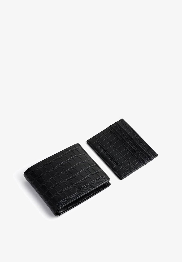 Czarny portfel i etui na karty wykonane z teksturowanej skóry z tłoczeniem w krokodyla. Portfel ma konstrukcję typu bi-fold; etui na karty jest smukłe i płaskie.