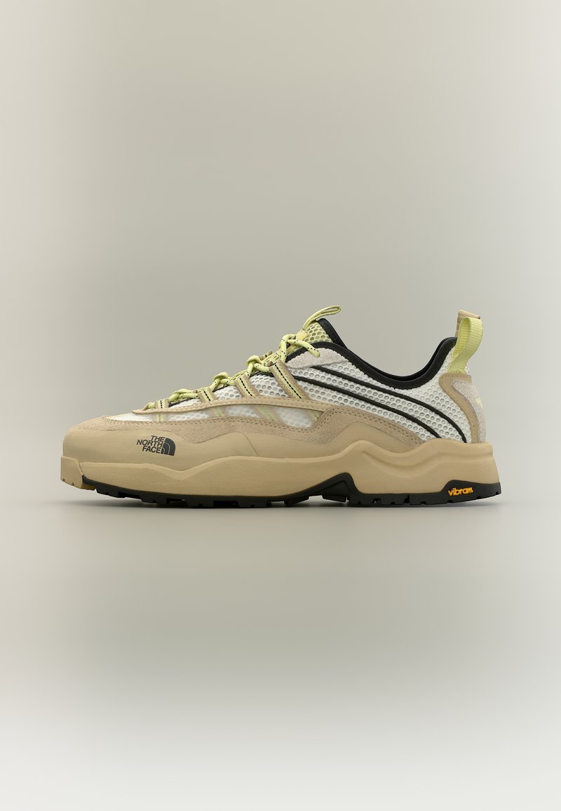Beež ja valge matkasuss võrgumaterjalist pealisega, kollased paelad, paks tekstureeritud talla, musta ja kollase Vibrami logoga ning The North Face'i logo küljel.