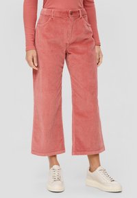 Person wearing high-waist wide-leg pink corduroy pants, long-sleeve matching top, and off-white platform sneakers on a plain background.