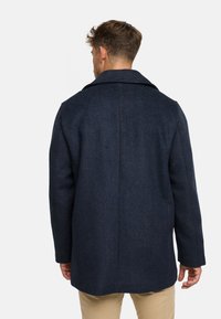 Abrigo de lana azul oscuro con un diseño estructurado, amplio cuello y mangas largas. Cuenta con un corte recto y una textura suave.