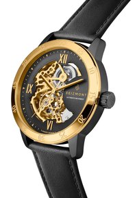 Svart lærrem klokke med en gull- og svart skjelettskive, markante gulltall for timene og synlige detaljer av automatisk mekanisme.