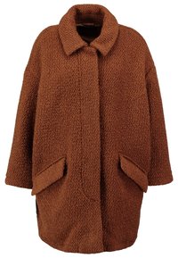 Brun fuskepälsjacka med krage, oversizemodell, texturerad yta och två framfickor, utan knappar.