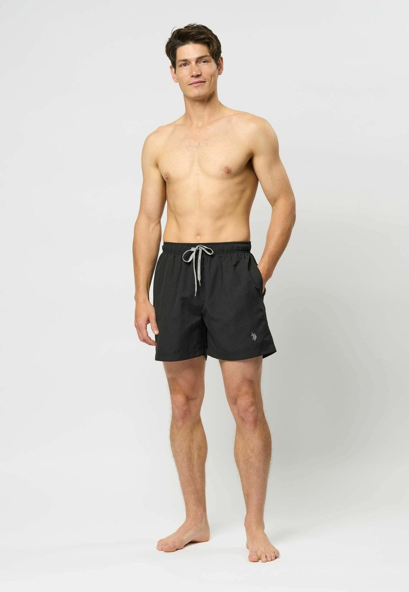 Čierne plavky s elastickým pásom, šnúrkou na stiahnutie a bočnými vreckami. Obsahuje diskrétny logotyp na ľavom stehne.