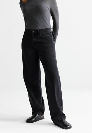 Black denim jeans with a loose fit, featuring front pockets, a button closure, and a slightly faded texture. Paired with a gray long-sleeve top.