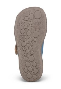 Semelle de chaussure d'enfant avec des empreintes de pas en relief, un visage de singe souriant, des formes de cœur et de fleur sur une surface texturée.