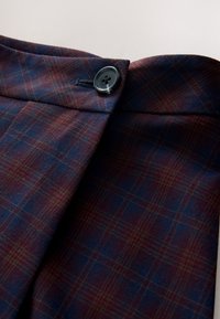 Kariran material v mornarsko modri in bordo barvi, z gladko teksturo in črnim gumbom na pasu. Izdelano z oprijetim krojem.