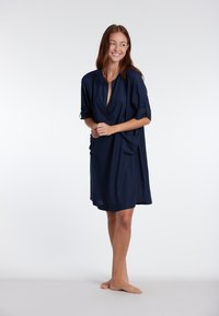 Abito blu navy con profonda scollatura a V, maniche corte e due tasche laterali. Tessuto leggero e morbido con vestibilità rilassata.