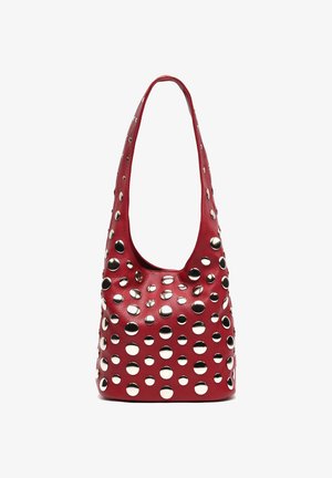 Sac à épaule en cuir rouge avec de grands et petits clous circulaires en argent couvrant l'avant et la bandoulière, sur fond blanc.