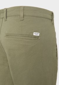 Olivgrüne Hose aus Baumwollmischgewebe, mit einer Gesäßtasche und einem gestickten Logo-Tag sowie klaren, maßgeschneiderten Linien.