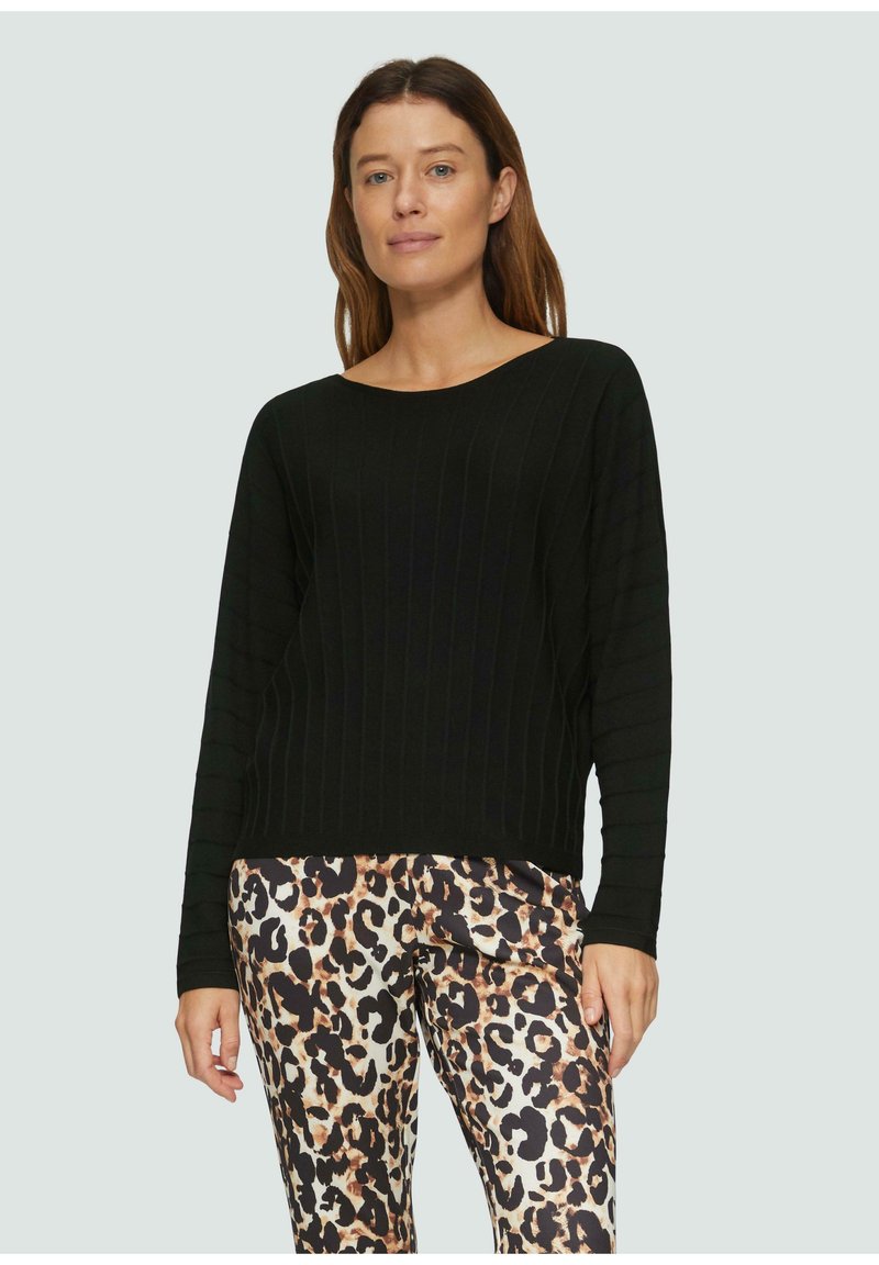Schwarzer gerippter Pullover mit langen Ärmeln, rundem Halsausschnitt und strukturiertem Muster, kombiniert mit einer Hose im Leopardenmuster mit glatter Oberfläche.