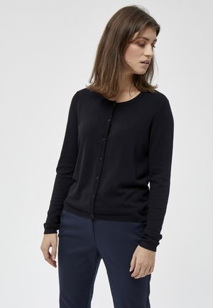 Musthave mustriga nööbidest kardigan, millel on pikad varrukad, valmistatud pehmest ja kergest kangast. Omab ümmargust kaelust ning soonikkoes mansette ja äärt.