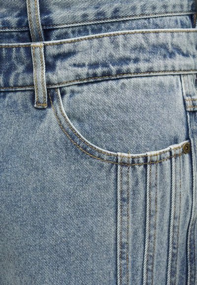 Ανοιχτό μπλε τζιν ύφασμα με μπροστινή τσέπη, θηλιά για ζώνη και ορατές ραφές, που δείχνουν υφή και ξεθωριαστά σχέδια.