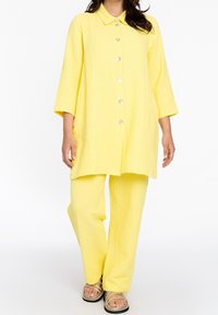 Geel katoenen outfit met een oversized overhemd met knopen, een kraag, driekwartmouwen en bijpassende broek met wijde pijpen. Getextureerde stof.