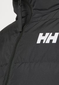 Gros plan d'une doudoune noire avec capuche, fermeture éclair avant et logo blanc "HH" sur la poitrine.