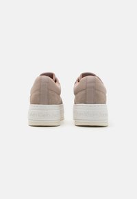 Sneaker Calvin Klein Jeans con tomaia in suede rosa chiaro e pelle, suola piatta bianca e nome del marchio impresso sul tallone.