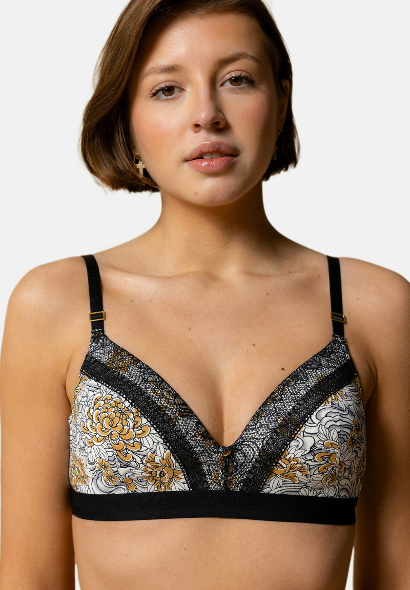 Soutien-gorge noir en dentelle avec un motif floral, orné de fleurs jaunes et blanches, présentant un décolleté plongeant et des bretelles ajustables.