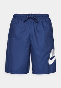 Granatowe spodenki kąpielowe wykonane z lekkiego materiału, posiadające elastyczny pas z sznurkiem oraz duże białe logo Nike z boku.