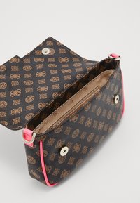 Sac à main marron à motif, fabriqué en matériau texturé avec des accents roses, doté d'une fermeture à bouton et de compartiments intérieurs. Vue ouverte.