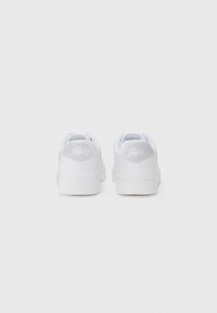 Hvite sneakers med en glatt skinnoverflate, subtilt semsket hælakkent, og tykk gummisåle, designet for uformell bruk.