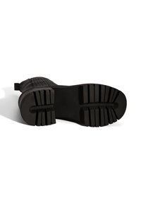 Zwarte rubberen zool met een textuurdesign, gekenmerkt door diepe groeven voor grip en een platte basis, ideaal voor stabiliteit op verschillende oppervlakken.