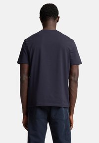 Marinblå t-shirt med korta ärmar, tillverkad av bomull, har en rund halsringning och en enkel design. Bakifrån syns en jämn textur.