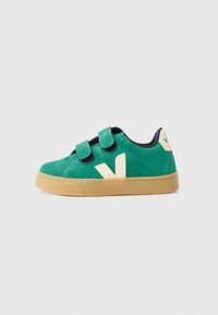 Sapatilha verde de camurça com correias de velcro, detalhes em bege, sola de borracha e um logótipo em relevo da letra "V" na lateral. Com interior azul-marinho.
