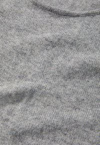 Grauer Strickstoff mit einer glatten Textur, der ein dezentes Melange-Muster und einen Rundhalsausschnitt aufweist. Leicht zerknitterte Oberflächendetails.