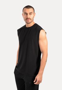 Schwarzes ärmelloses T-Shirt aus weichem Stoff, mit rundem Ausschnitt und lockerer Passform. Minimalistisches Design ohne sichtbare Muster oder Grafiken.