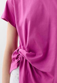 Fuchsia katoenen T-shirt met een relaxed fit, voorzien van een zij-knoopdetail en korte mouwen. Zachte textuur, casual stijl.