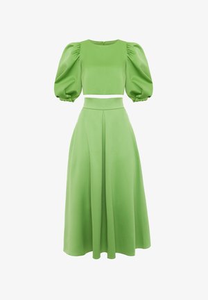Zielony zestaw składający się z dwóch części, zawierający krótki top z bufkami oraz spódnicę o wysokim stanie, sięgającą do ziemi, wszystko wykonane z gładkiego, teksturowanego materiału.