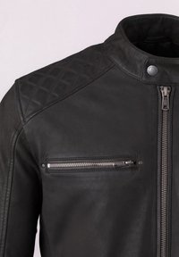 Black leather jacket featuring a quilted design on the shoulders, silver zippers, and a snap button collar; textured surface is smooth with matte accents.