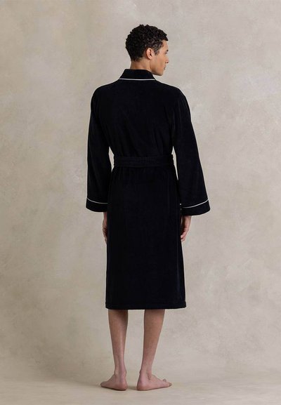 Μαύρο μπουρνούζι από πετσέτα με μακριά μανίκια, ζώνη και λευκή λεπτομέρεια κατά μήκος του γιακα και των μανικιών. Λείο, υφασμένο φινίρισμα.