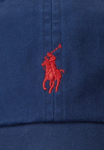 Gorra de béisbol azul marino hecha de algodón con una visera curva. Presenta un prominente logo bordado en rojo de un jugador de polo en la parte frontal.
