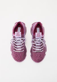 Chaussures de sport violettes au design moucheté, empeigne en mesh texturé, lacets blancs et languette avec logo. Semelles robustes pour un bon maintien.