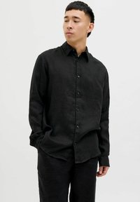 Camisa de lino negra de manga larga con botonadura frontal, cuello clásico y un corte relajado, que presenta una textura sutil y sin patrones visibles.