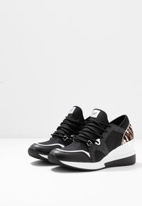 Černé sportovní boty z různých materiálů, včetně textilu a kůže. Elegantní design s bílými detaily a leopardím vzorem na patě.