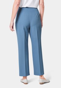 Maßgeschneiderte blaue Hosen mit vertikalen Nähten, die einen hohen Bund und weite Beine aufweisen. Das Material scheint glatt mit einem subtilen Glanz zu sein.