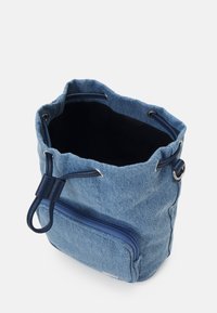 Sac seau en denim bleu avec cordon de serrage, poche avant zippée et doublure intérieure noire.