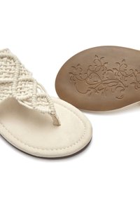 Sandales tressées beige avec une semelle intérieure en daim plate et une semelle extérieure marron ornée de gravures florales. Les lanières sont finement tressées.