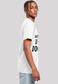 Tricou alb cu mânecă scurtă și guler rotund, având inscripția mare în text negru "CE FACI U" pe față. Croială casual.