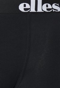 Svarta boxerkalsonger i bomullsblandning har en bred elastisk midjeband med vit branding. Tyget verkar slätt med minimal textur.