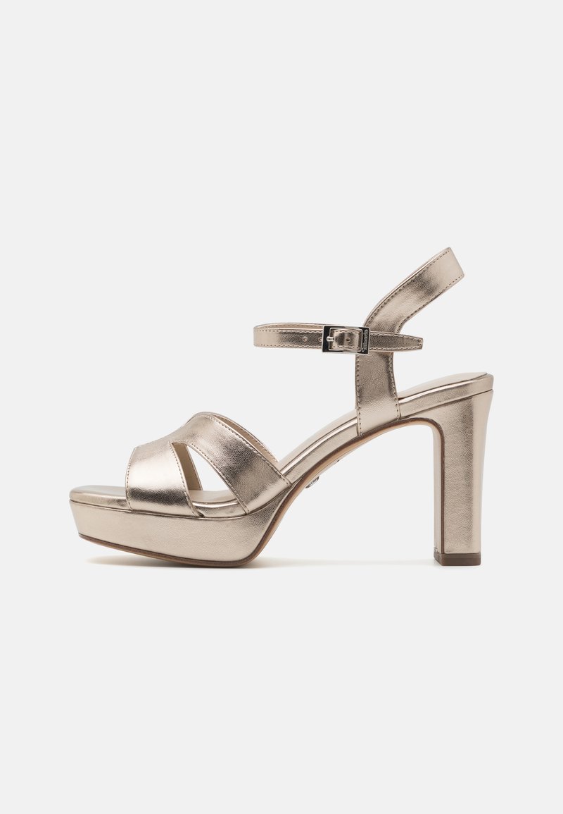Sandale à talons hauts en métal doré avec une bride de cheville et une boucle, semelle compensée et bout ouvert sur un fond blanc.