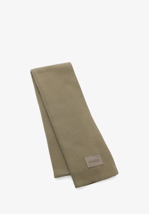 Zielono-oliwkowy szalik wykonany z miękkiego materiału, o prostokątnym kształcie, z markową łatą w jaśniejszym kolorze na jednym końcu.