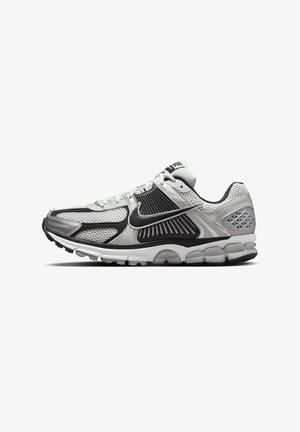 Zapatillas de correr Nike en negro, blanco y gris. Cuentan con una parte superior de malla y sintético, cuello acolchado y suela de goma con tecnología de amortiguación.