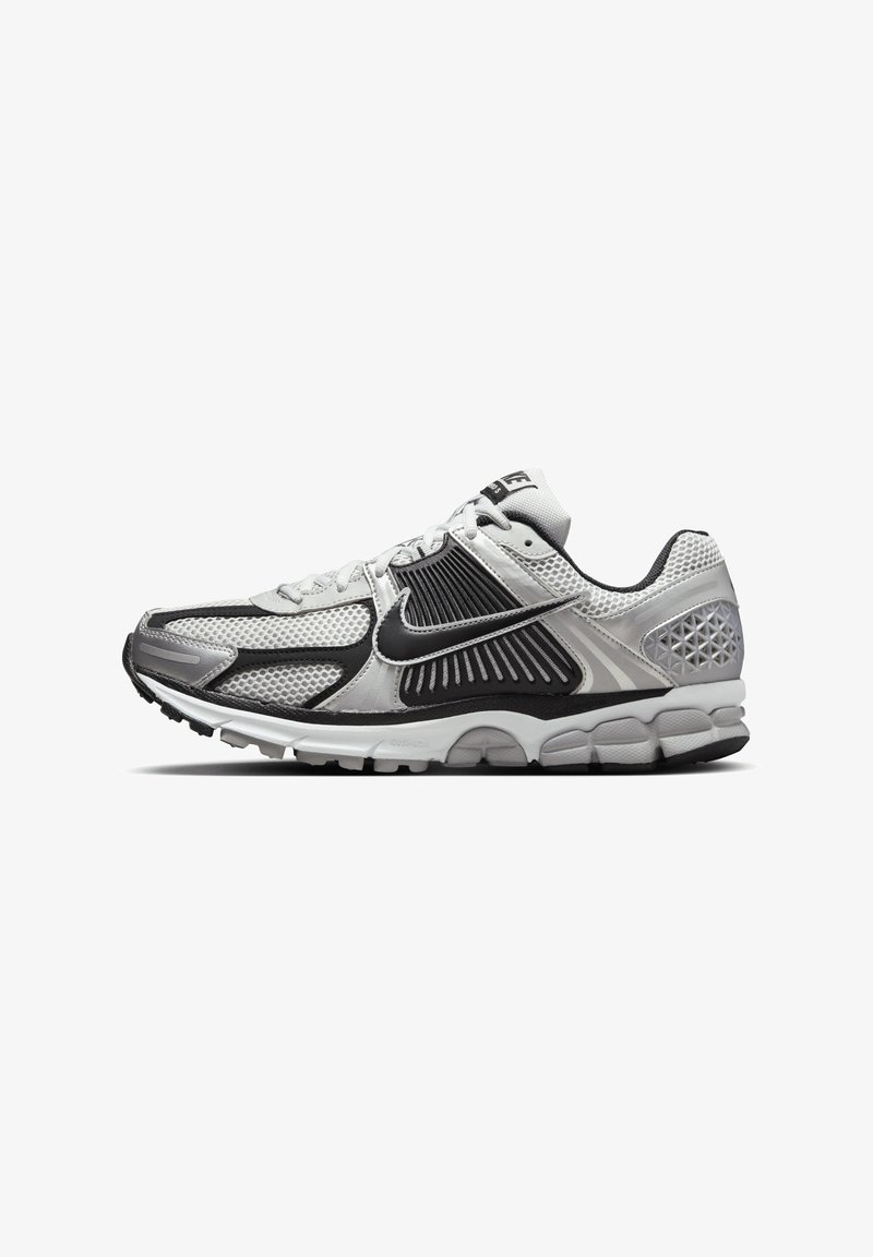 Sapatilhas de corrida Nike em preto, branco e cinza. Apresentam um cabedal em malha e sintético, colarinho acolchoado e sola em borracha com tecnologia de amortecimento.