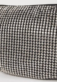 Bolso de mano negro cubierto con pequeños strass plateados, con una textura suave y cierre de cremallera en el borde superior.