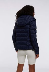 Granatowa kurtka puchowa z kapturem, z pikowanym wzorem, poziomym przeszyciem oraz naszywką z logo na lewym rękawie.